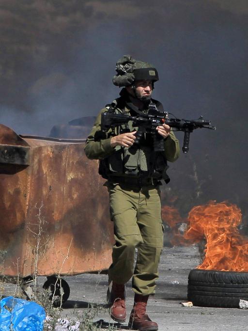 Ein bewaffneter israelischer Soldat steht neben brennenden Reifen während Auseinandersetzungen mit Palästinensern nahe einer jüdischen Siedlung bei Ramallah.
