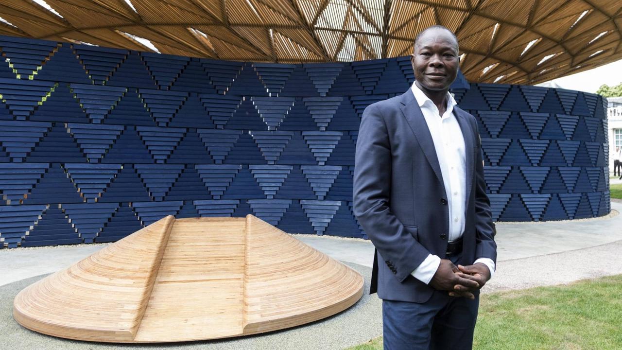 Architekt Francis Kéré vor dem von ihm entworfenen Serpentine Gallery Summer Pavilion 2017. Architekt Francis Kéré vor dem von ihm entworfenen Serpentine Gallery Summer Pavilion 2017.
