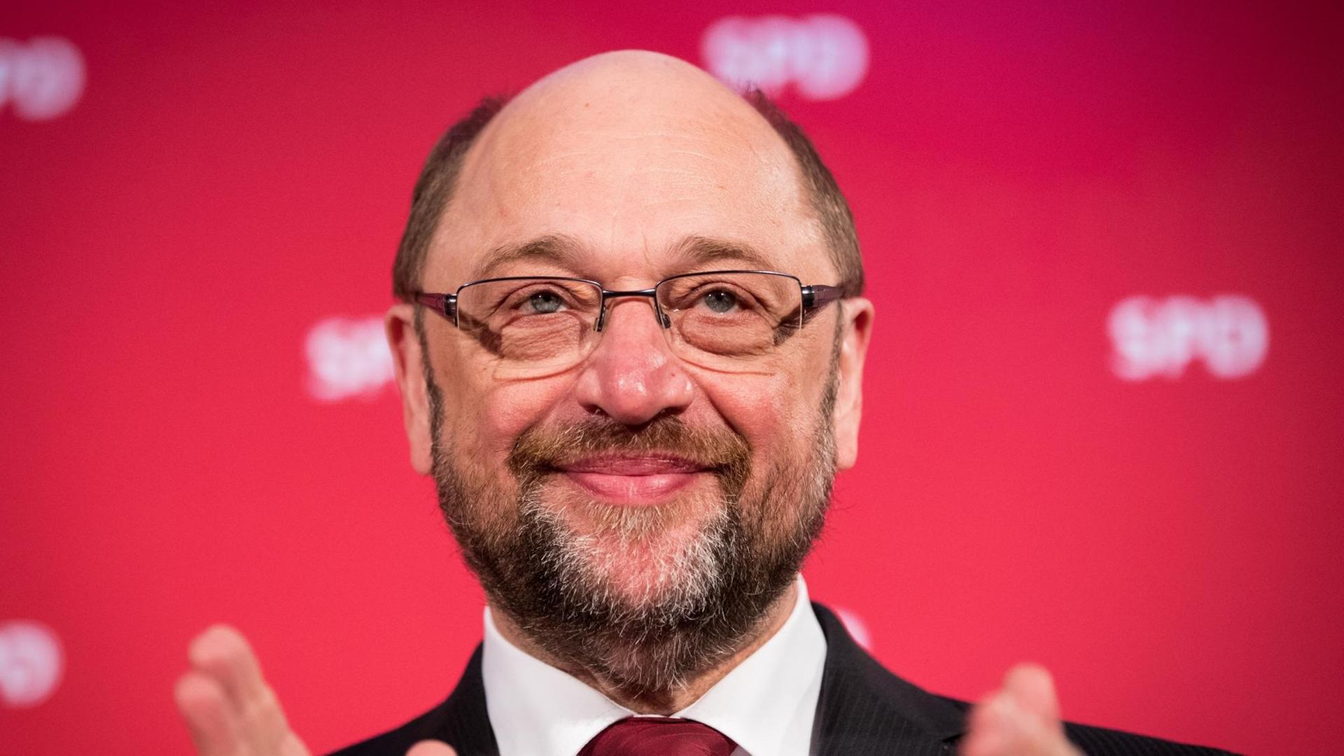 Der SPD-Kanzlerkandidat Martin Schulz lächelnd vor einer Wand mit SPD-Logos.