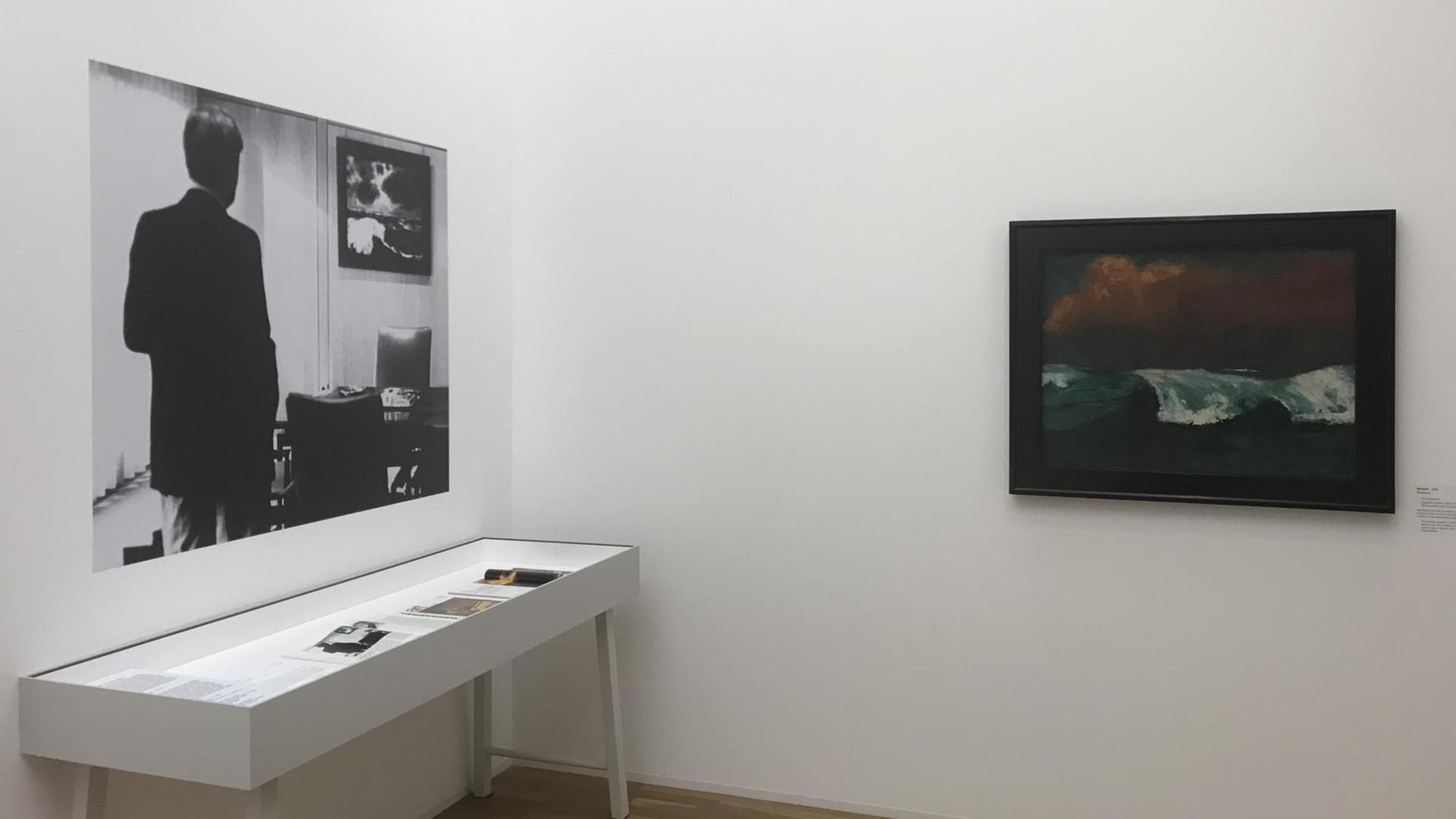 Ausstellungsansicht: Ein Foto von Helmut Schmidt im Bonner Kanzleramt mit "seinem" Nolde "Meer III" und daneben der "Brecher" von 1936 aus dem Amtszimmer von Angela Merkel. Die Ausstellung "Emil Nolde - Eine deutsche Legende. Der Künstler im Nationalsozialismus", 12.4. – 15.9.2019, Hamburger Bahnhof - Museum für Gegenwart Berlin Ausstellungsansicht: Ein Foto von Helmut Schmidt im Bonner Kanzleramt mit "seinem" Nolde "Meer III" und daneben der "Brecher" von 1936 aus dem Amtszimmer von Angela Merkel. Die Ausstellung "Emil Nolde - Eine deutsche Legende. Der Künstler im Nationalsozialismus", 12.4. – 15.9.2019, Hamburger Bahnhof - Museum für Gegenwart Berlin
