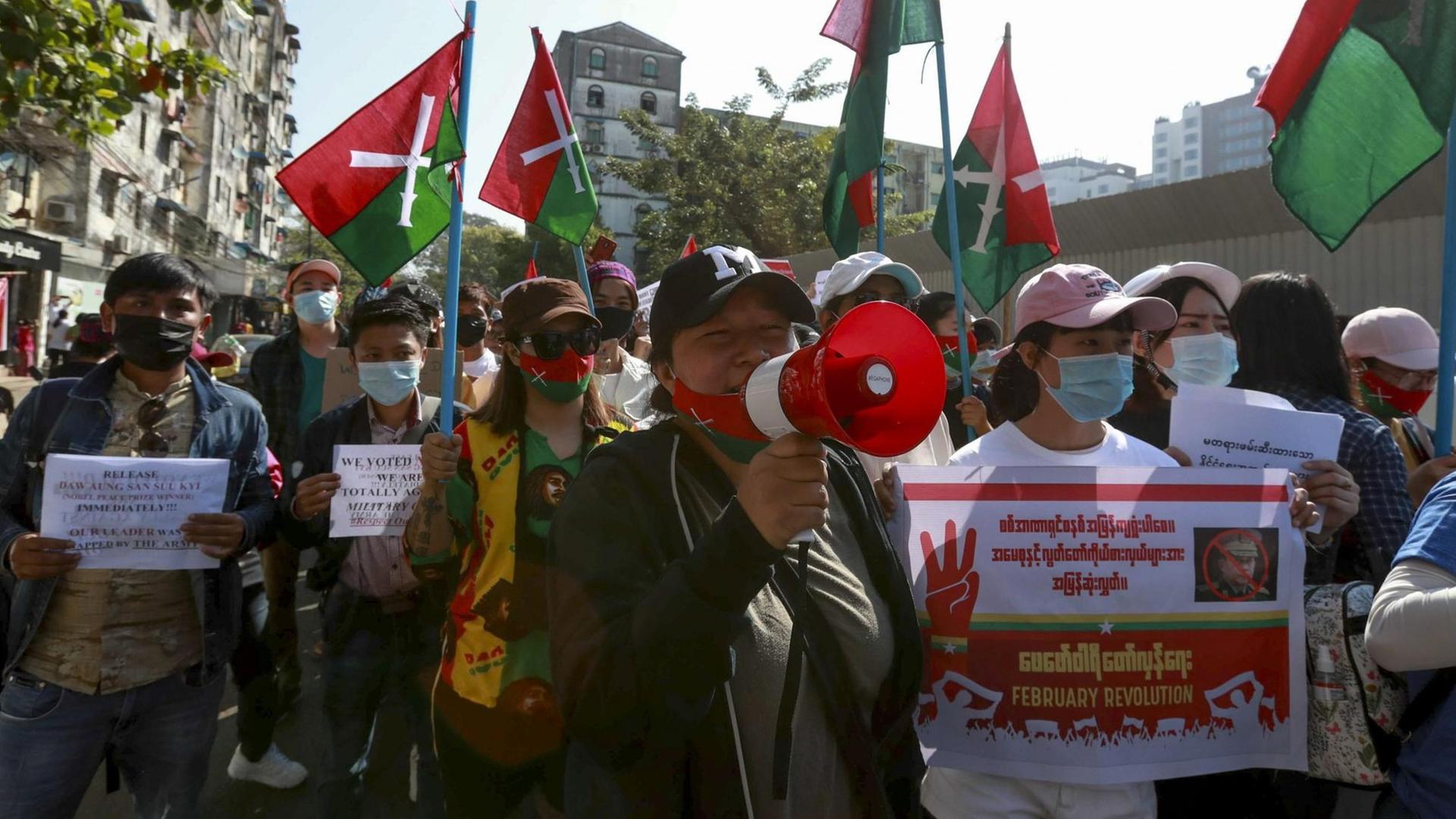 Demonstranten in Yangon, Myanmar mit Plaketen und Lautsprechern.