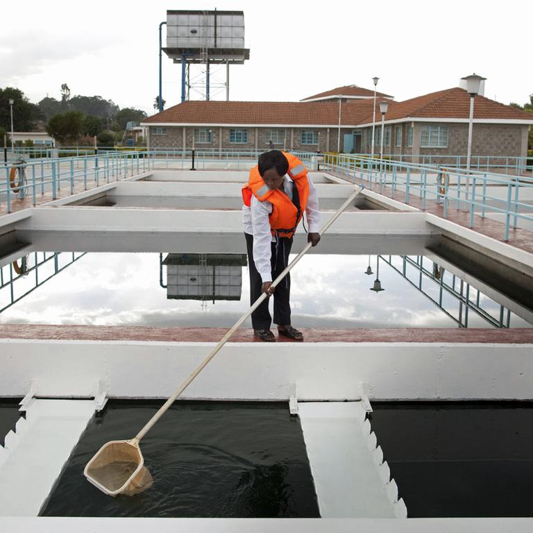 Eine Frau in Sicherheitsweste entfernt Schmutz aus einem Wasserbecken in einem Pumpwerk in Nyeri in Kenia, aufgenommen 2012
