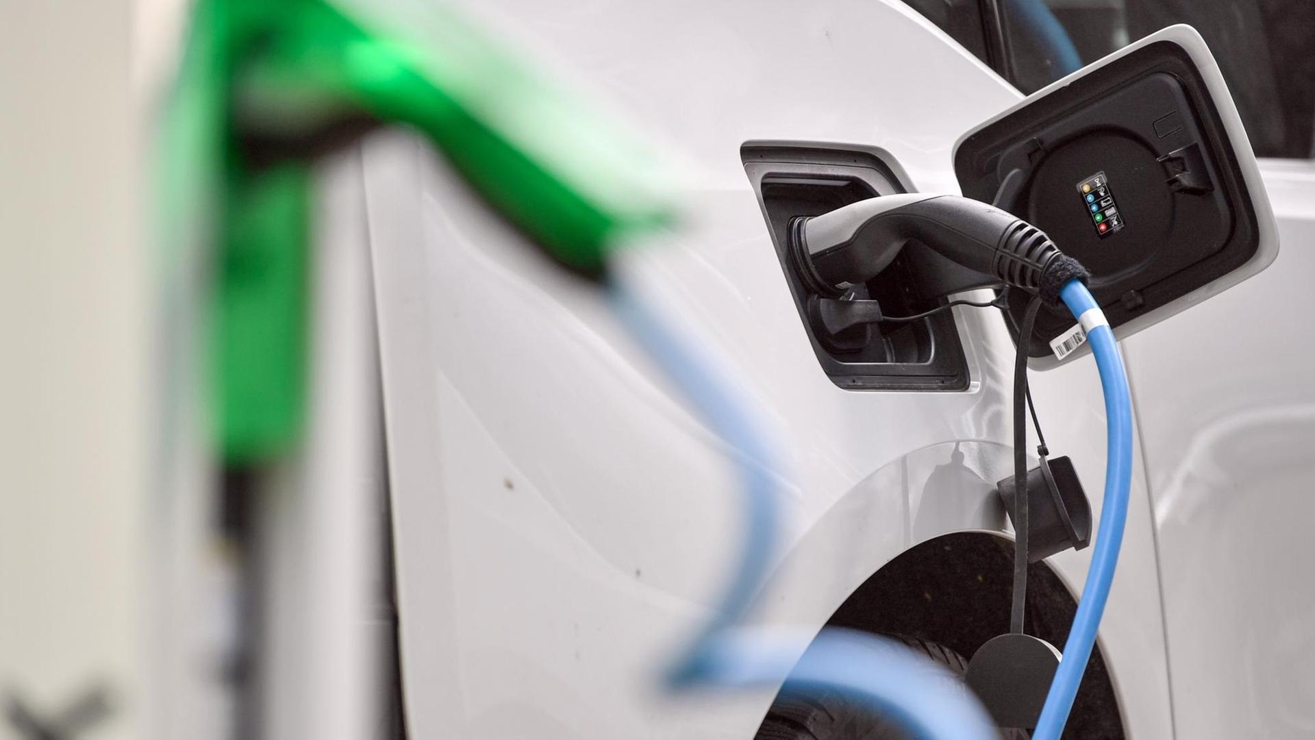 Ein weißes Elektrofahrzeug vom Typ BMW i3 wird an einer E-Tankstelle aufgeladen Ein weißes Elektrofahrzeug vom Typ BMW i3 wird an einer E-Tankstelle aufgeladen