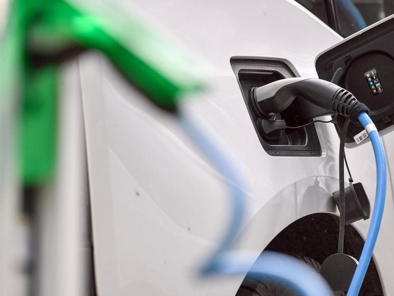 Ein weißes Elektrofahrzeug vom Typ BMW i3 wird an einer E-Tankstelle aufgeladen