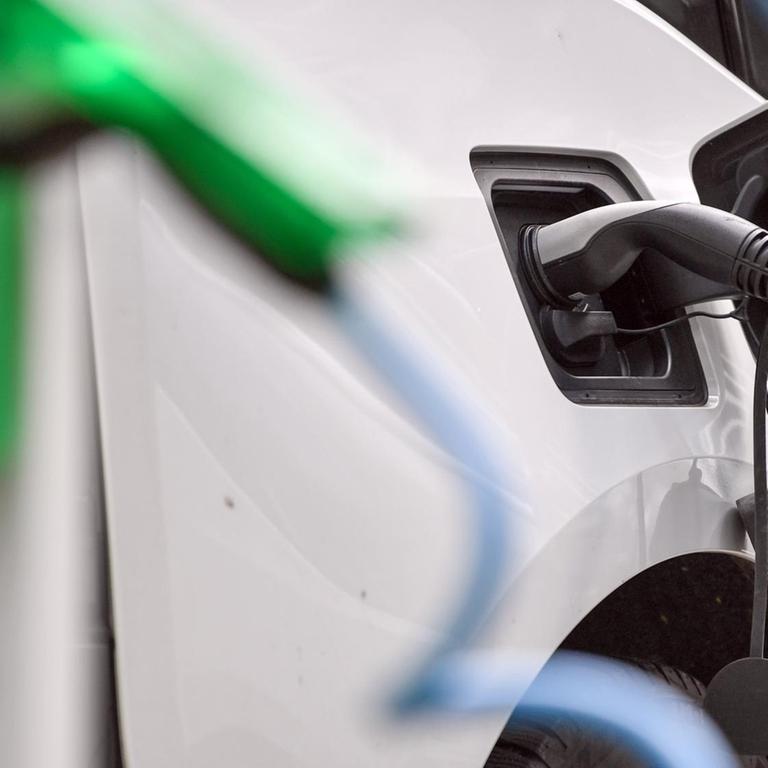 Ein weißes Elektrofahrzeug vom Typ BMW i3 wird an einer E-Tankstelle aufgeladen
