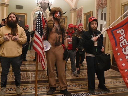 Trump-Unterstützer mit US- und Trump-Flaggen stehen im Kapitol.