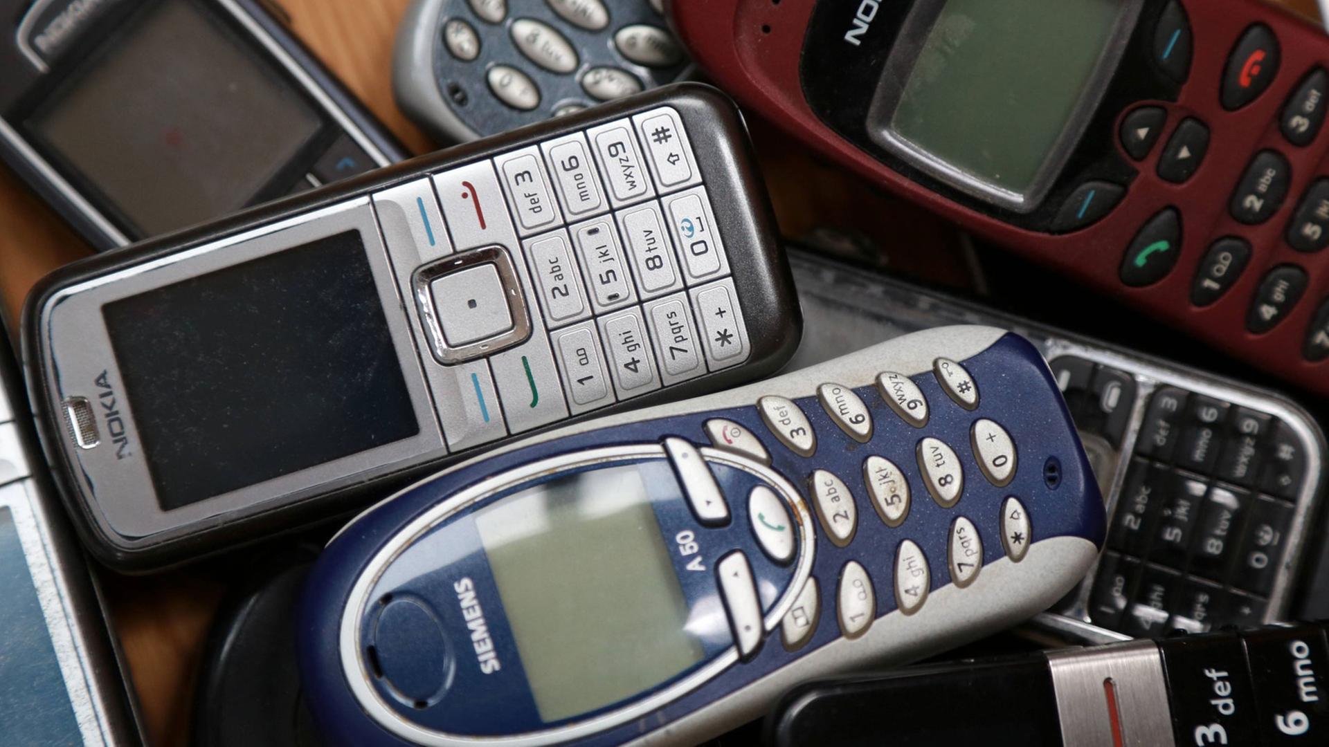 Mehrere ausgediente Mobiltelefone liegen auf einem Tisch. Mehrere ausgediente Mobiltelefone liegen auf einem Tisch.