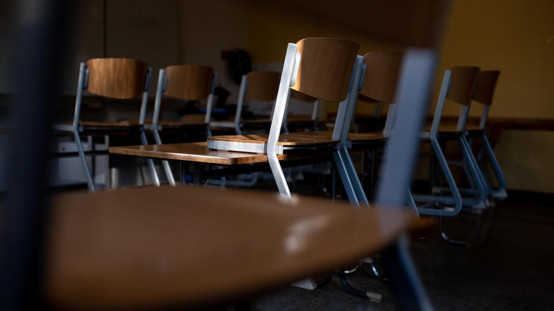 Ein leeres Klassenzimmer in dem Stühle auf den Tischen stehen.