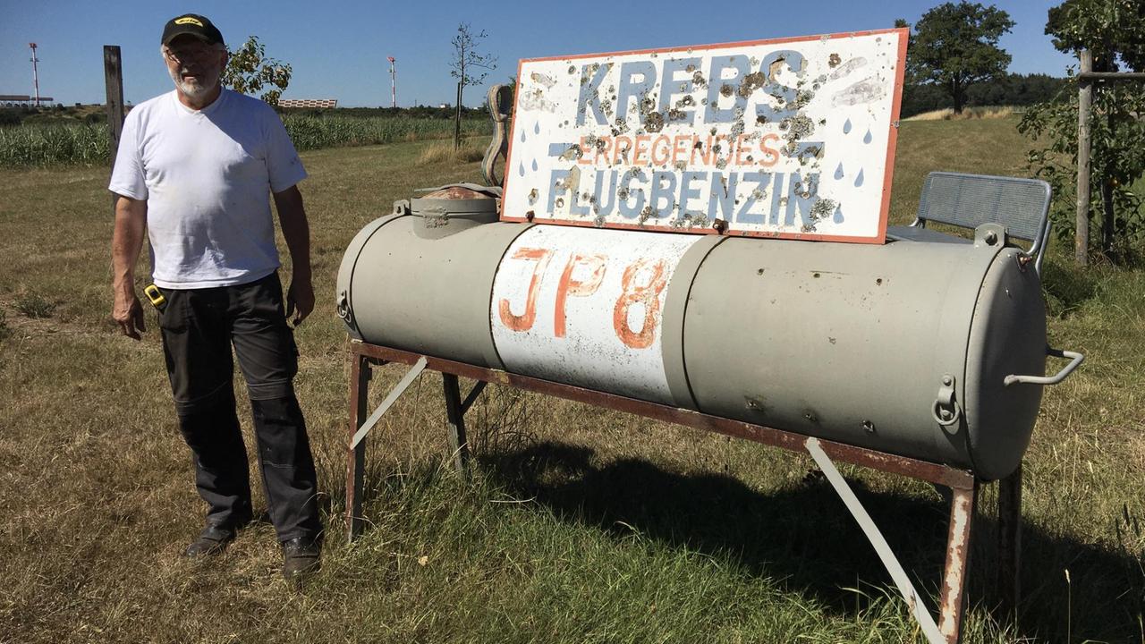 Ein Mann steht vor einem Tank mit der Aufschrift Ein Mann steht vor einem Tank mit der Aufschrift