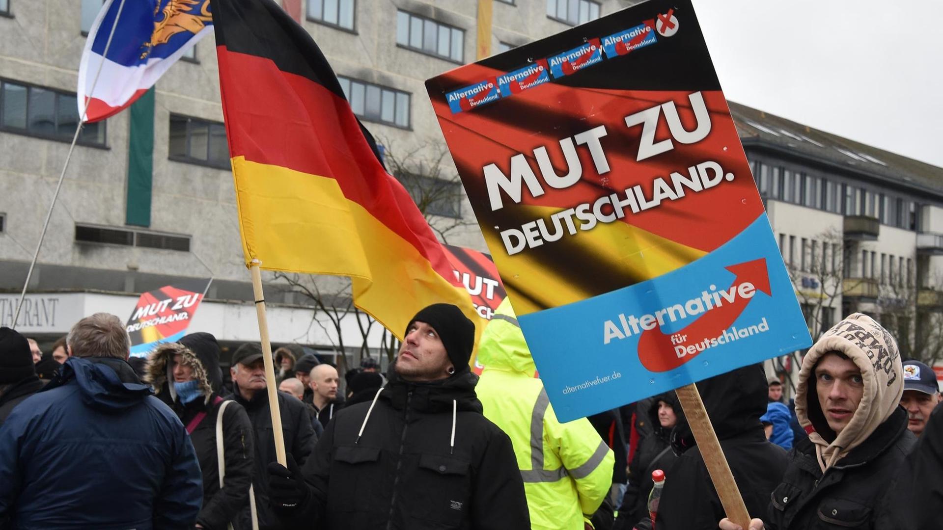 Mit Plakaten und Fahnen stehen AfD-Anhänger in Neubrandenburg auf dem Marktplatz.