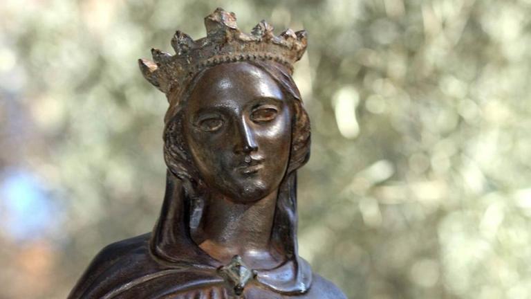 Bronzestatue einer jungen Frau mit Krone, die mild lächelt, in einem Park stehend. Bronzestatue einer jungen Frau mit Krone, die mild lächelt, in einem Park stehend.