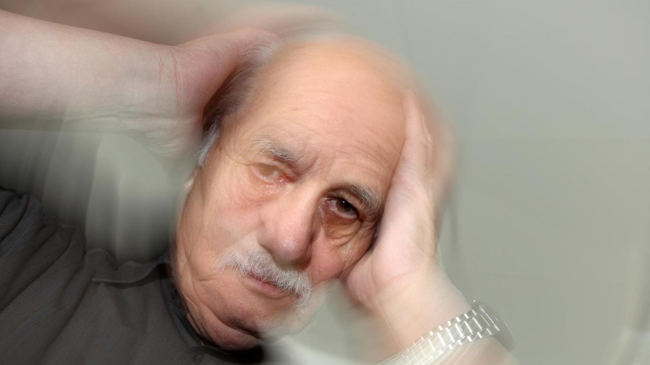 Ein älterer Mann fast sich an den Kopf Ein älterer Mann fast sich an den Kopf