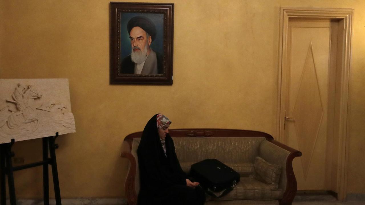 Eine iranische Staatsangestellte hört in der iranischen Botschaft im Libanon einer Pressekonferenz zu. Über ihr hängt ein Bild von Ayatollah Khomeini. Eine iranische Staatsangestellte hört in der iranischen Botschaft im Libanon einer Pressekonferenz zu. Über ihr hängt ein Bild von Ayatollah Khomeini.