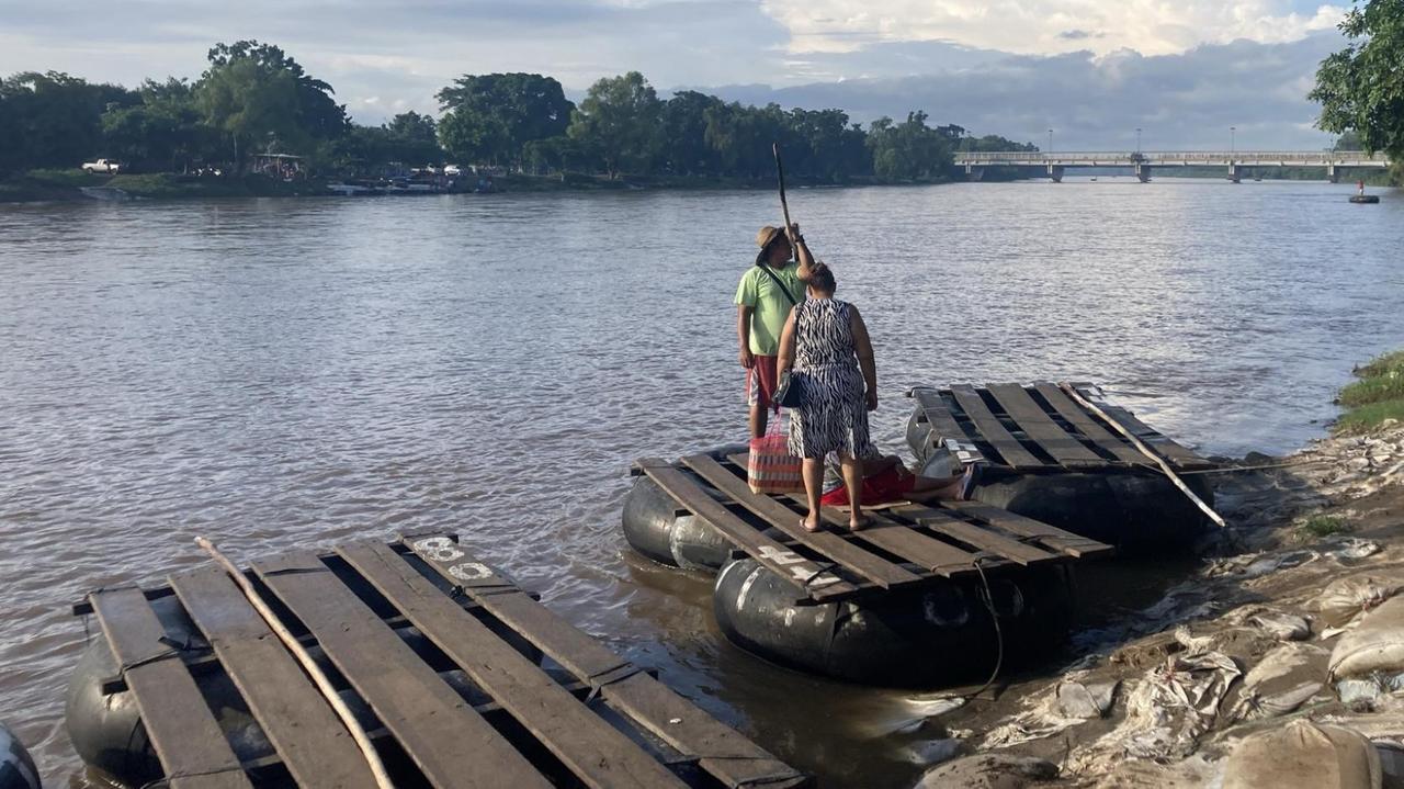 Zwei Personen stehen auf einem von drei Flößen am Ufer des Rio Suchiate.