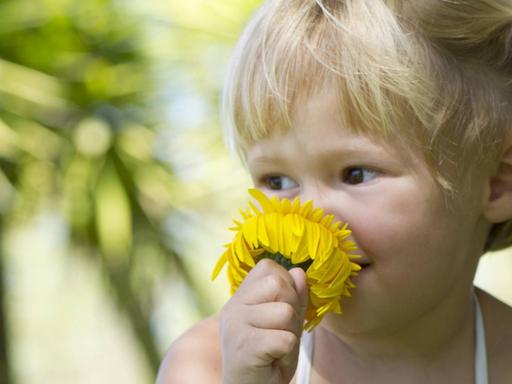Ein Kind riecht an einer Blume.