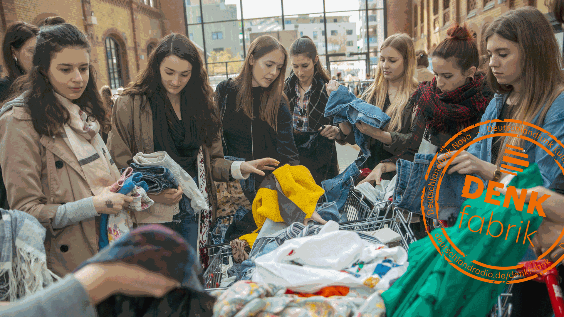 Auf einer Kleidertauschparty: Junge Frauen durchsuchen zwei Einkaufswagen nach Kleidungsstücken. Auf einer Kleidertauschparty: Junge Frauen durchsuchen zwei Einkaufswagen nach Kleidungsstücken.