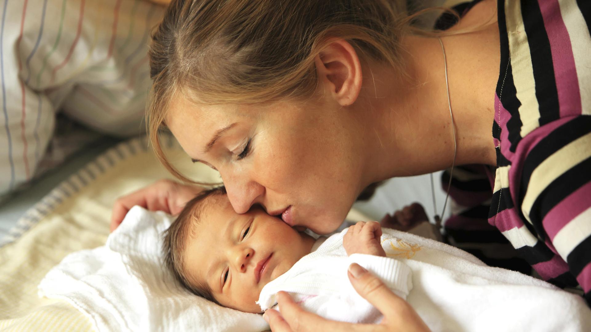 Eine Frau küsst ihr Baby auf die Wange. Eine Frau küsst ihr Baby auf die Wange.