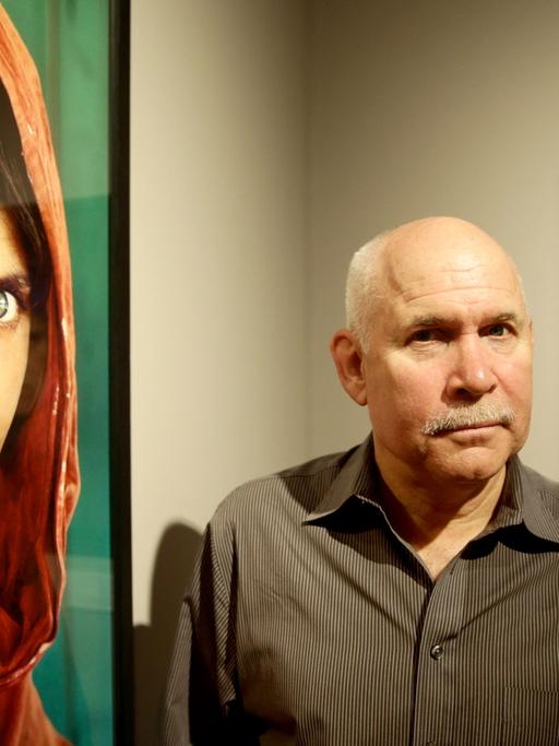 Der US-amerikanische Fotograf Steve McCurry 2013 in der Ausstellung "Steve McCurry. Überwältigt vom Leben" im Museum für Kunst und Gewerbe in Hamburg zwischen seinen Bildern.