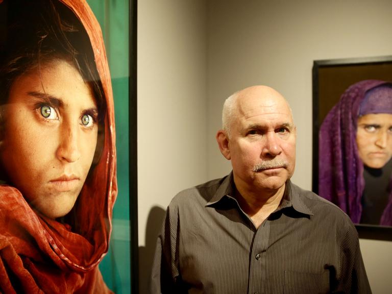 Der US-amerikanische Fotograf Steve McCurry 2013 in der Ausstellung "Steve McCurry. Überwältigt vom Leben" im Museum für Kunst und Gewerbe in Hamburg zwischen seinen Bildern.