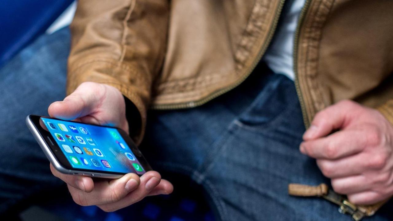 Ein junger Mann sitzt am 03.03.2017 in Frankfurt am Main (Hessen) in einer S-Bahn und benutzt dabei sein Smartphone. Ein junger Mann sitzt am 03.03.2017 in Frankfurt am Main (Hessen) in einer S-Bahn und benutzt dabei sein Smartphone.
