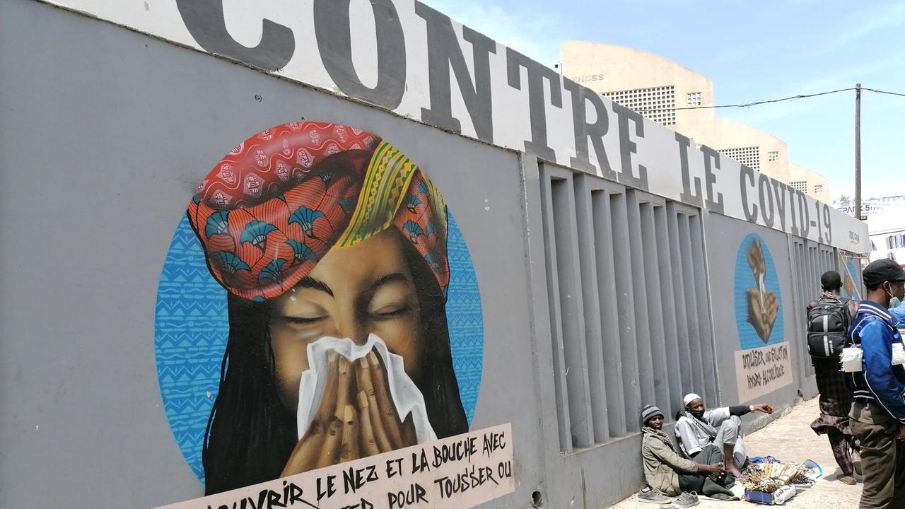 Ein Anti-Corona-Graffiti in Senegals Hauptstadt Dakar zwischen der Uniklinik Fann und dem Uni-Campus. Eine Frau hält sich ein Taschentuch vor die Nase.