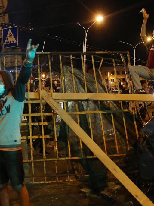 Anhänger der Opposition stehen in Minsk nachts vor und auf einer errichteten Barrikade und demonstrieren gegen das Ergebnis der Präsidentschaftswahl in Belarus.