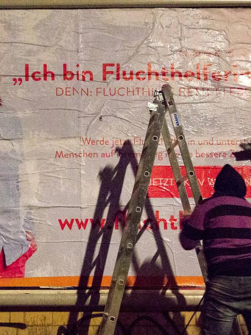Peng-Aktivisten plakatieren in der Nähe der Berliner Ausländerbehöre ein Plakat mit der Aufschrift: "Ich bin Fluchthelferin!" Am selben Tag startete eine Kampagne für zivilen Ungehorsam, in dem die Aktivisten Urlauber zur Fluchthilfe auffordern.