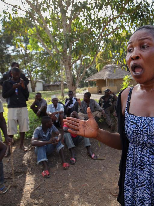 Eine klagende Frau in einem Dorf in Liberia, hinter ihr sitzen ein Dutzend Menschen