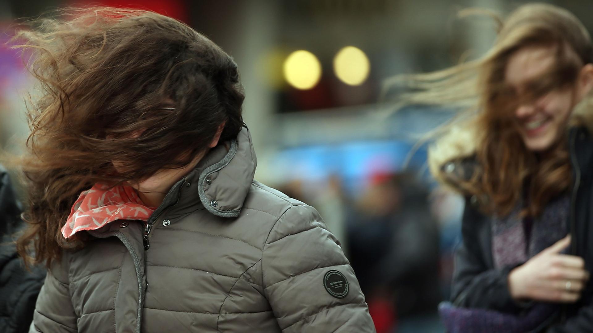 Wind wirbelt die Haare von Fußgängern durcheinander. Wind wirbelt die Haare von Fußgängern durcheinander.