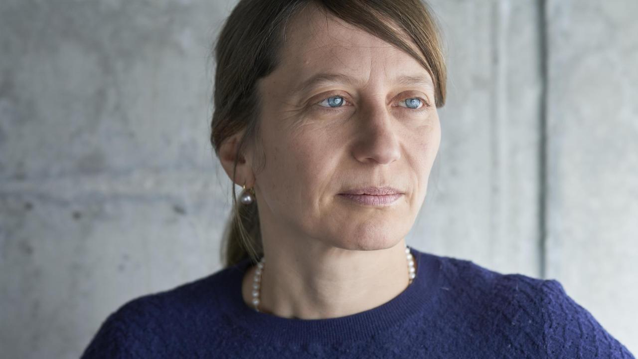 Eine Frau mit hellen blauen Augen und braunem Pferdeschwanz schaut sinnend in die Ferne. Eine Frau mit hellen blauen Augen und braunem Pferdeschwanz schaut sinnend in die Ferne.