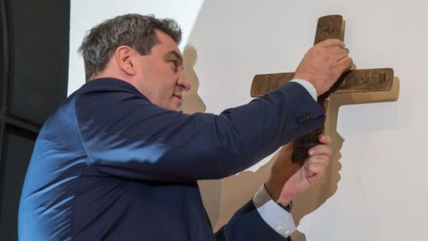 Der bayerische Ministerpräsident Markus Söder hängt in der Bayerischen Staatskanzlei ein Kreuz auf.