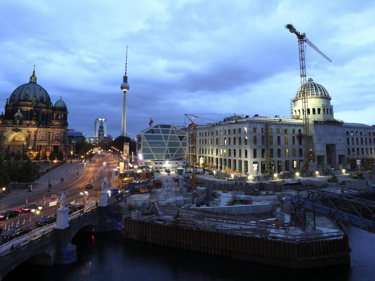 Das Berliner Stadtschloss im Bau, neben Dom und Fernsehturm bei Dämmerung.