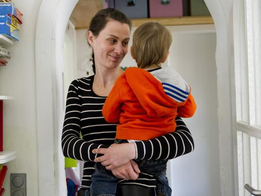 Die Tagesmutter Gina Schuster hält in Ratingen (Nordrhein-Westfalen) ein Kind auf dem Arm.
