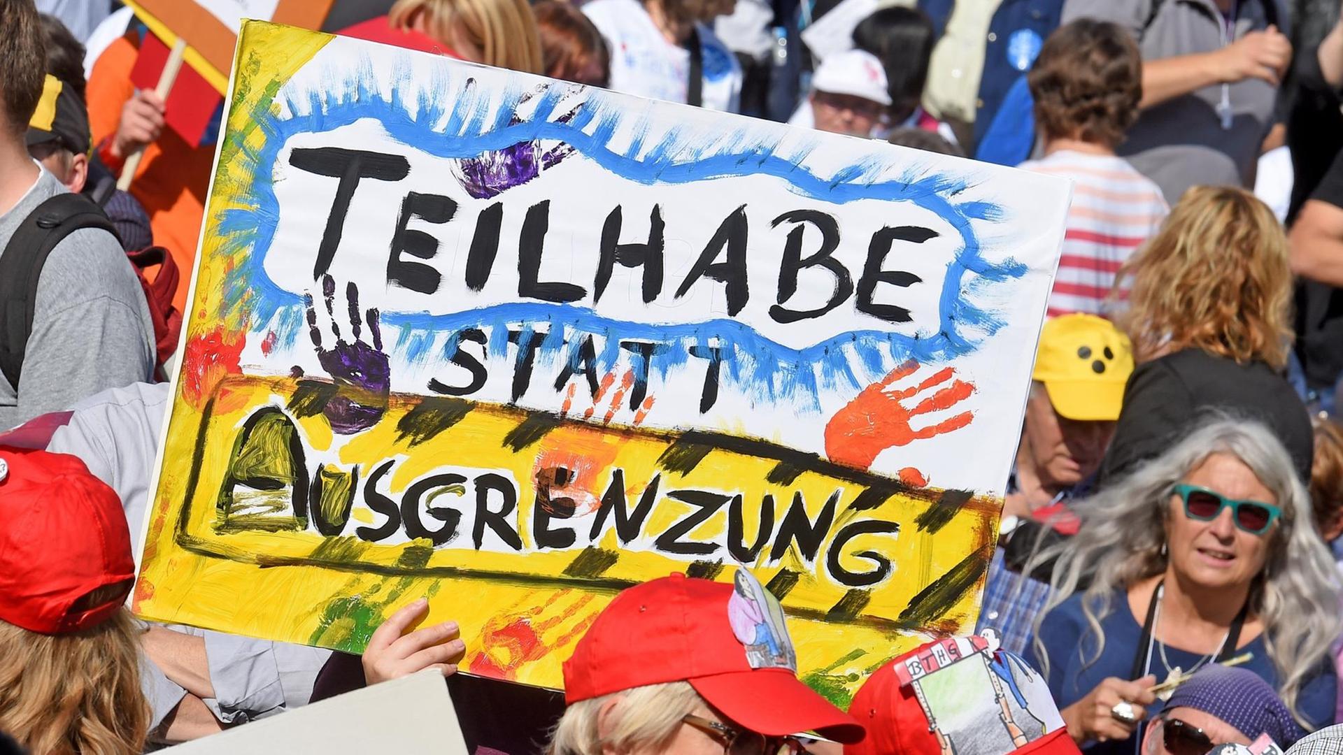 Mit Plakaten versammeln sich tausende Menschen mit Behinderung in Hannover. Auf einem Plakat steht "Teilhabe statt Ausgrenzung". Mit Plakaten versammeln sich tausende Menschen mit Behinderung in Hannover. Auf einem Plakat steht "Teilhabe statt Ausgrenzung".