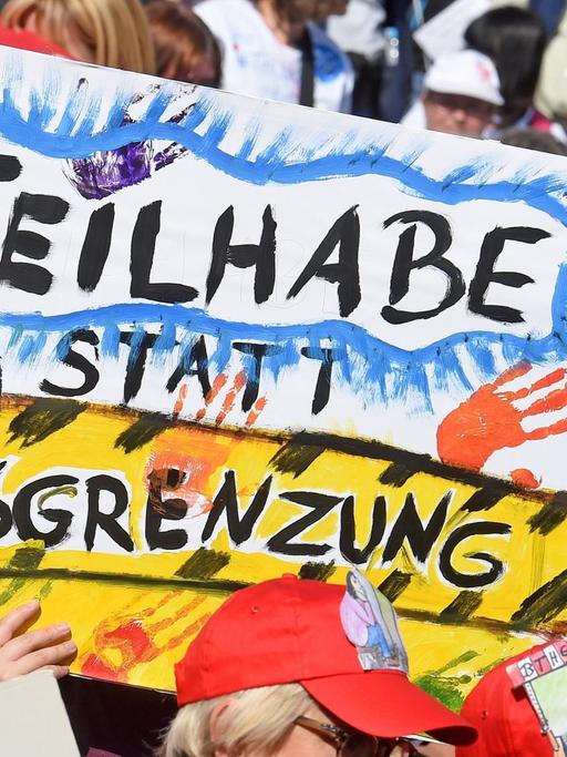 Mit Plakaten versammeln sich tausende Menschen mit Behinderung in Hannover. Auf einem Plakat steht "Teilhabe statt Ausgrenzung".