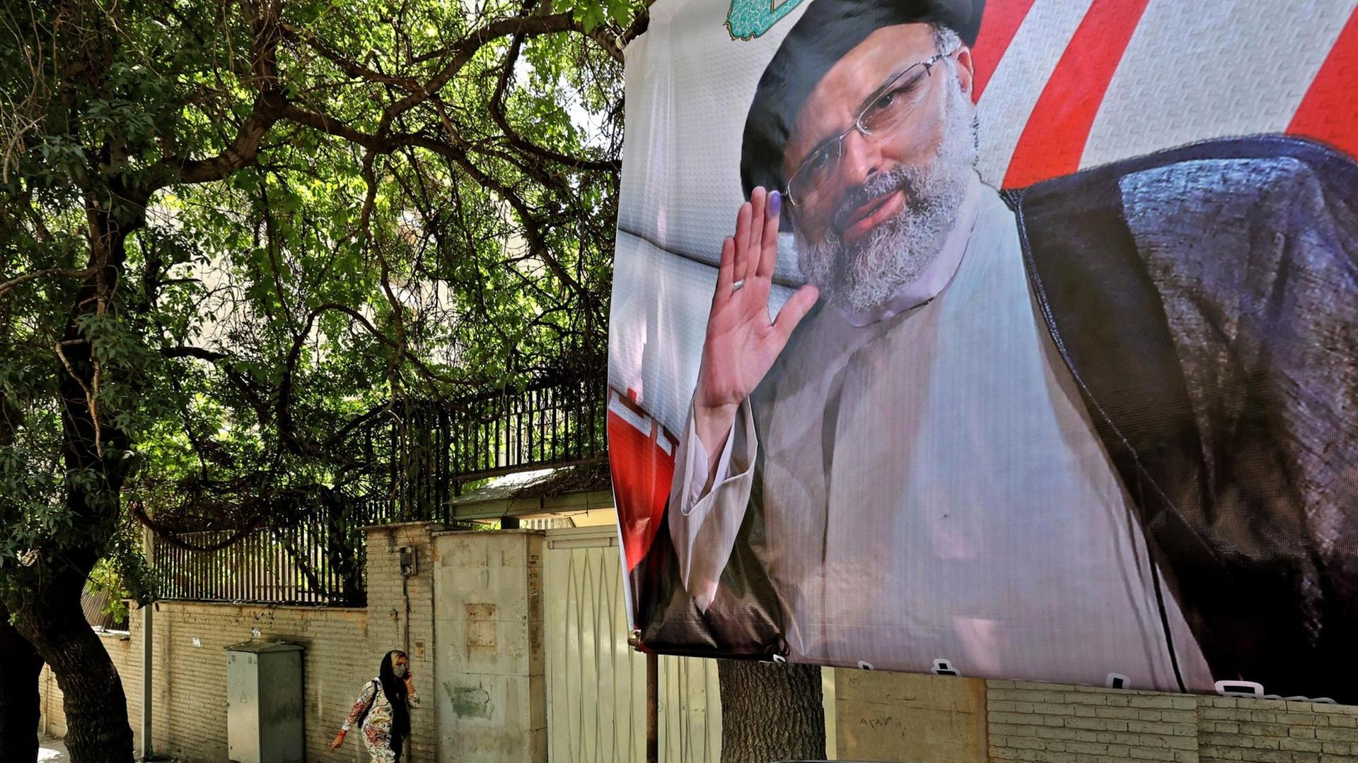 Ein Fußgängerin geht in der iranischen Hauptstadt Teheran an einem Wahlplakat des Präsidentschaftskandidaten Ebrahim Raisi vorbei.
