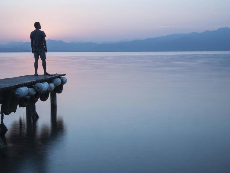 Ein Mann steht auf einem Steg am Gardasee in Italien, in Lazise.