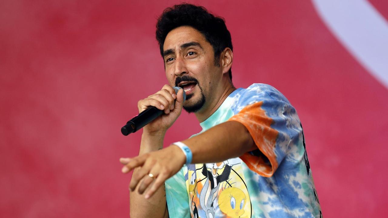 Der Rapper Eko Fresh bei einem Konzert, er trägt ein buntes T-Shirt und zeigt mit seiner linken Hand in Richtung Publikum