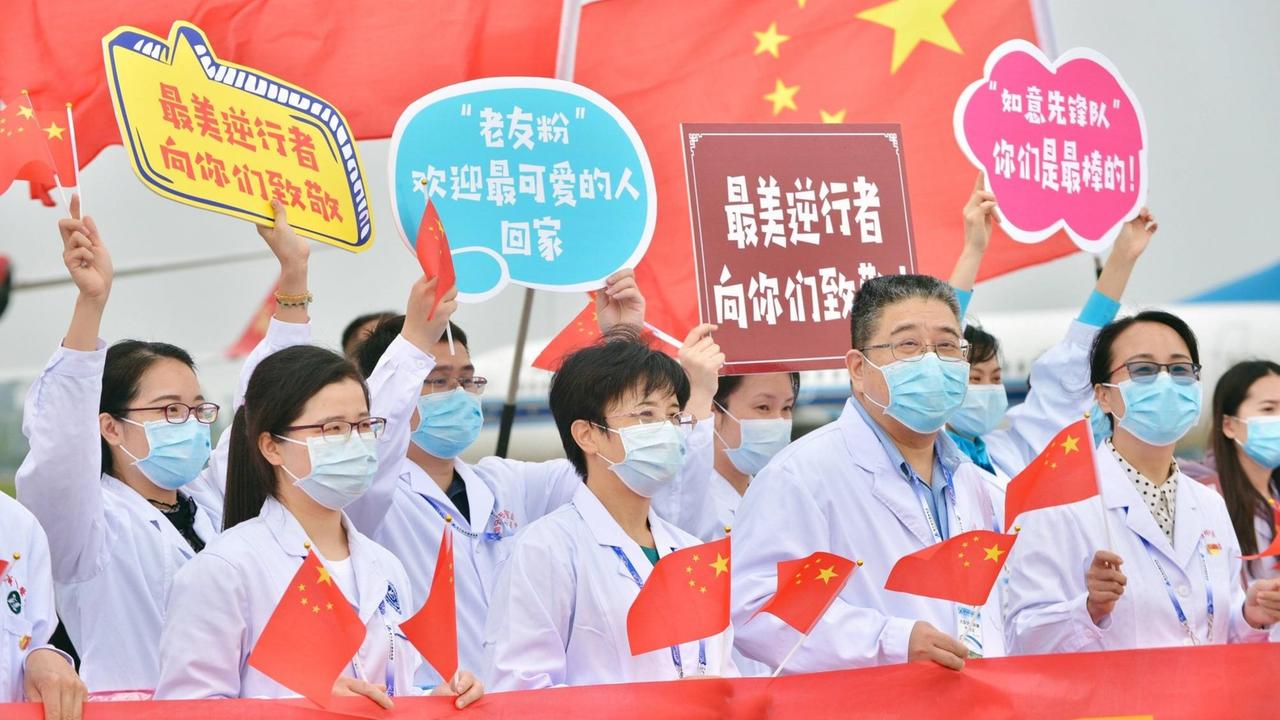Krankenhausmitarbeiter in der chinesischen Stadt Nanning, mit Kittel und Mundschutz bekleidet, halten Schilder und chinesische Flaggen hoch. Krankenhausmitarbeiter in der chinesischen Stadt Nanning, mit Kittel und Mundschutz bekleidet, halten Schilder und chinesische Flaggen hoch.