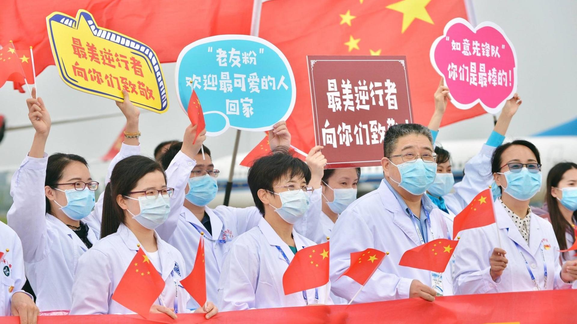 Krankenhausmitarbeiter in der chinesischen Stadt Nanning, mit Kittel und Mundschutz bekleidet, halten Schilder und chinesische Flaggen hoch. Krankenhausmitarbeiter in der chinesischen Stadt Nanning, mit Kittel und Mundschutz bekleidet, halten Schilder und chinesische Flaggen hoch.