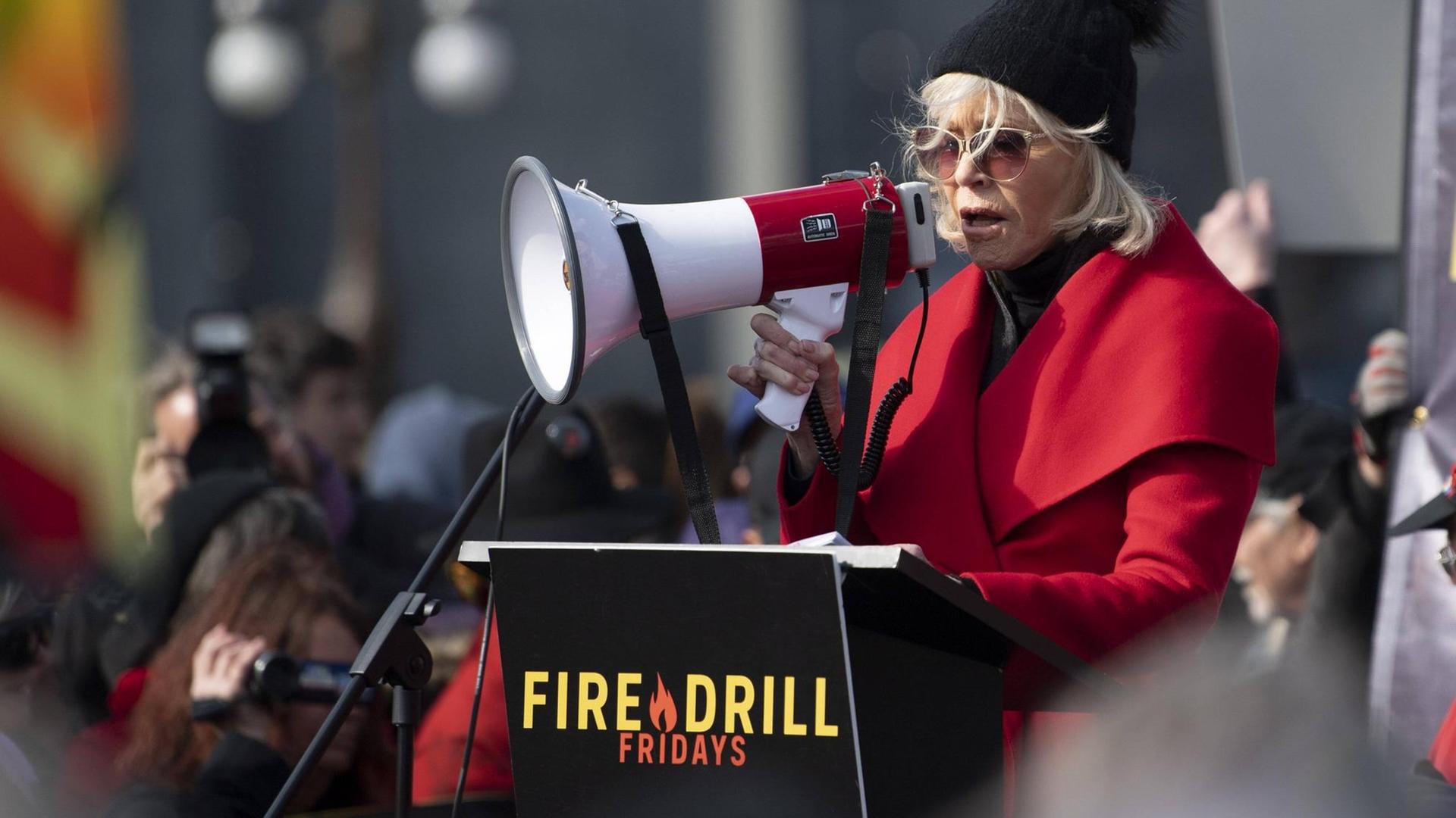 Jane Fonda steht im November 2019 bei einer Klimademo der "Fire Drill Fridays" in Washington, DC am Rednerpult und spricht durch ein Megafon