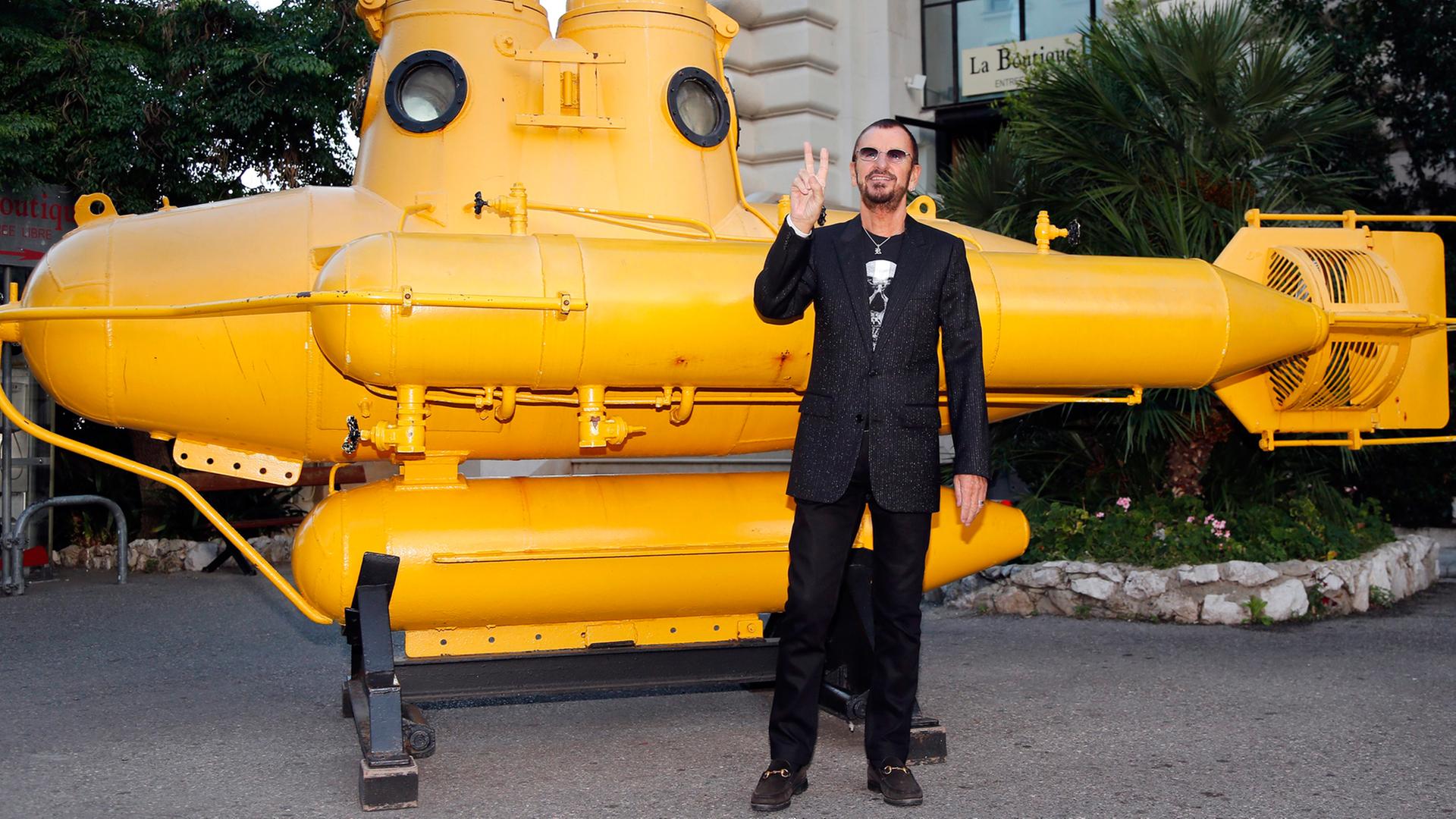 Beatle mit Yellow Submarine: Ringo Starr posiert vor einem gelben U-Boot. Beatle mit Yellow Submarine: Ringo Starr posiert vor einem gelben U-Boot.