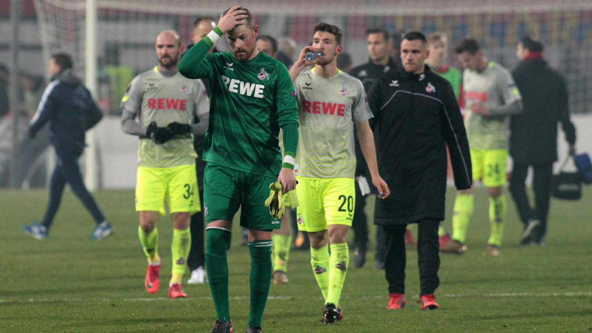 Die Spieler verlassen mit enttäuschten Gesichtern den Platz. Im Vordergrund Timo Horn im grünen Torwart-Trikot; er fasst sich an die Stirn. Die Spieler verlassen mit enttäuschten Gesichtern den Platz. Im Vordergrund Timo Horn im grünen Torwart-Trikot; er fasst sich an die Stirn.