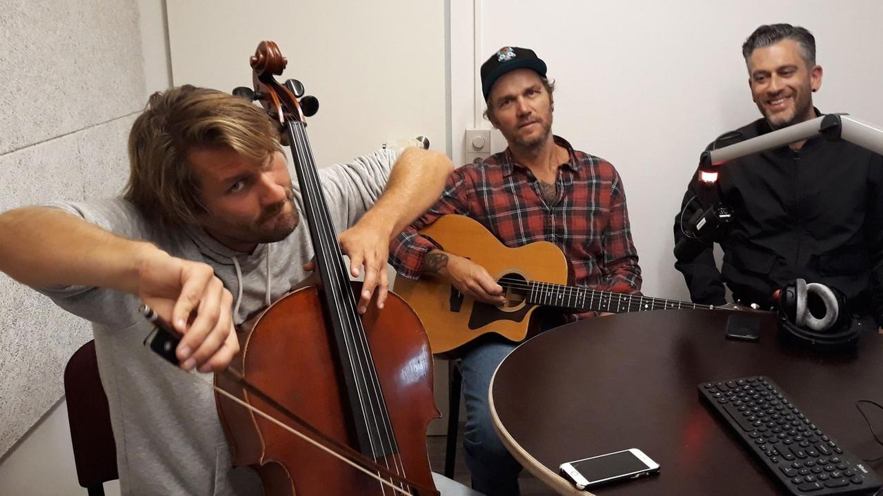 Ben Schaschek (l) und Hannes Koch  haben die Musikdoku "Blown away" gedreht. Drei Männer sitzen mit Instrumenten in eine Raum. 