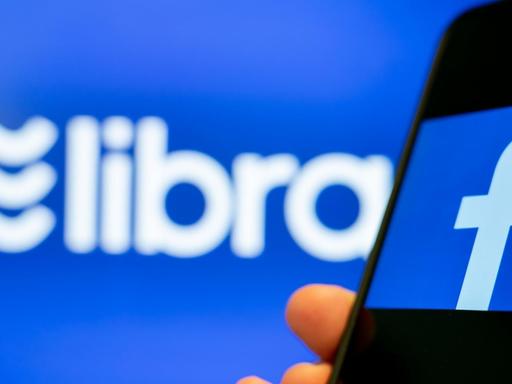 Ein Smartphone mit Facebook-App vor einem Libra-Logo.