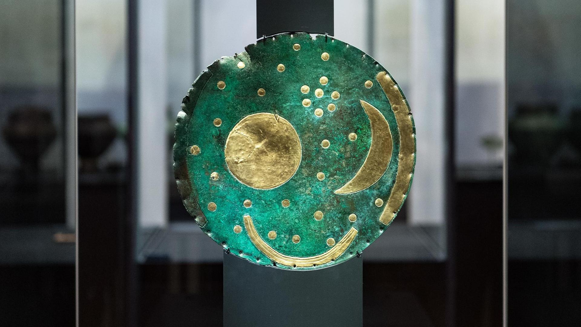Eine antike grüne Scheibe mit Sternsymbolen steht in einer Vitrine. Eine antike grüne Scheibe mit Sternsymbolen steht in einer Vitrine.