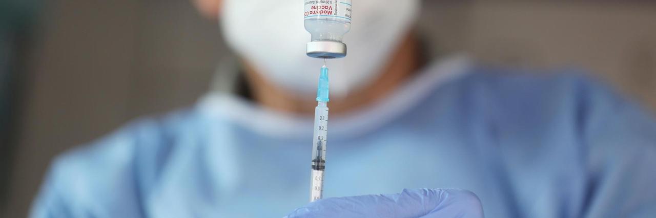 Ein Arzt zieht eine Spritze mit dem Impfstoff von Moderna aus einer Ampulle auf.
