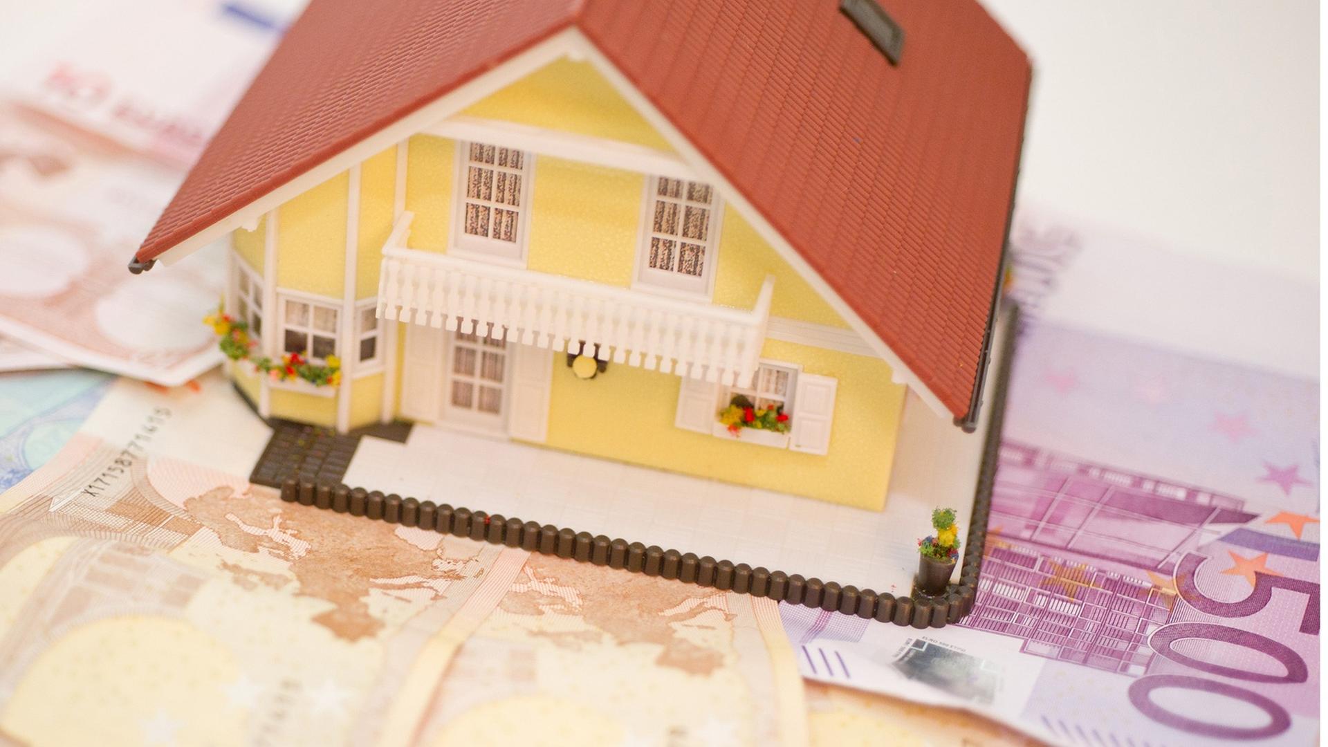 Ein Haus steht auf Geldscheinen. Symbolbild für Haus und seine Kosten Ein Haus steht auf Geldscheinen. Symbolbild für Haus und seine Kosten