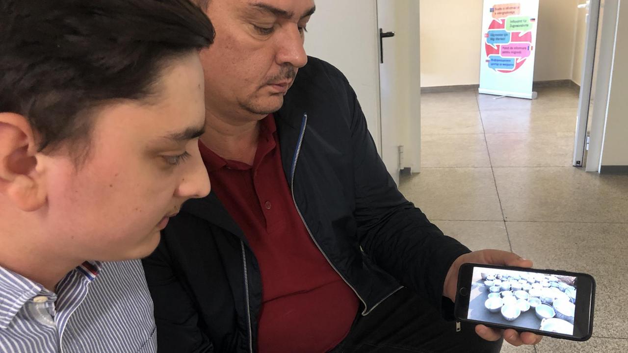 Diego Dinca und sein Vater Vasile sitzen beim Quartiermanagement in Hagen. Vater Vasile arbeitet bei einem Paketzusteller, hat dazu noch einen Job als Hausmeister. Auf dem Handy zeigt er Bilder aus seiner Heimat, aus Toflea, wo die Familie Dinca erfolgreiche Handwerker waren. Die Fotos zeigen große Schalen, Grillroste, alles aus Metall hergestellt. Diego Dinca und sein Vater Vasile sitzen beim Quartiermanagement in Hagen. Vater Vasile arbeitet bei einem Paketzusteller, hat dazu noch einen Job als Hausmeister. Auf dem Handy zeigt er Bilder aus seiner Heimat, aus Toflea, wo die Familie Dinca erfolgreiche Handwerker waren. Die Fotos zeigen große Schalen, Grillroste, alles aus Metall hergestellt.