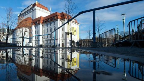 Das Schauspielhaus Dresden spiegelt sich in einer Pfütze.